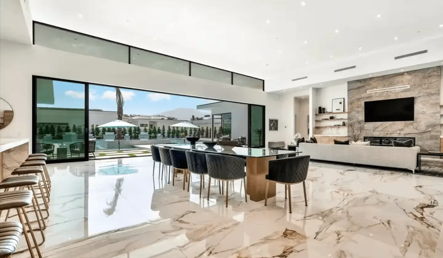 Open-plan living and dining area with floor-to-ceiling windows overlooking a pool.