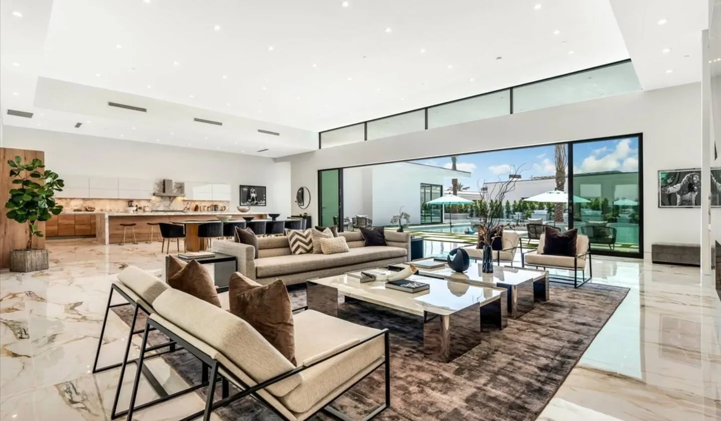 A spacious living room opens onto a patio through large glass windows.