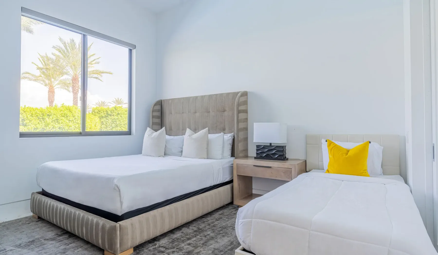 A bedroom with two beds and a large window.