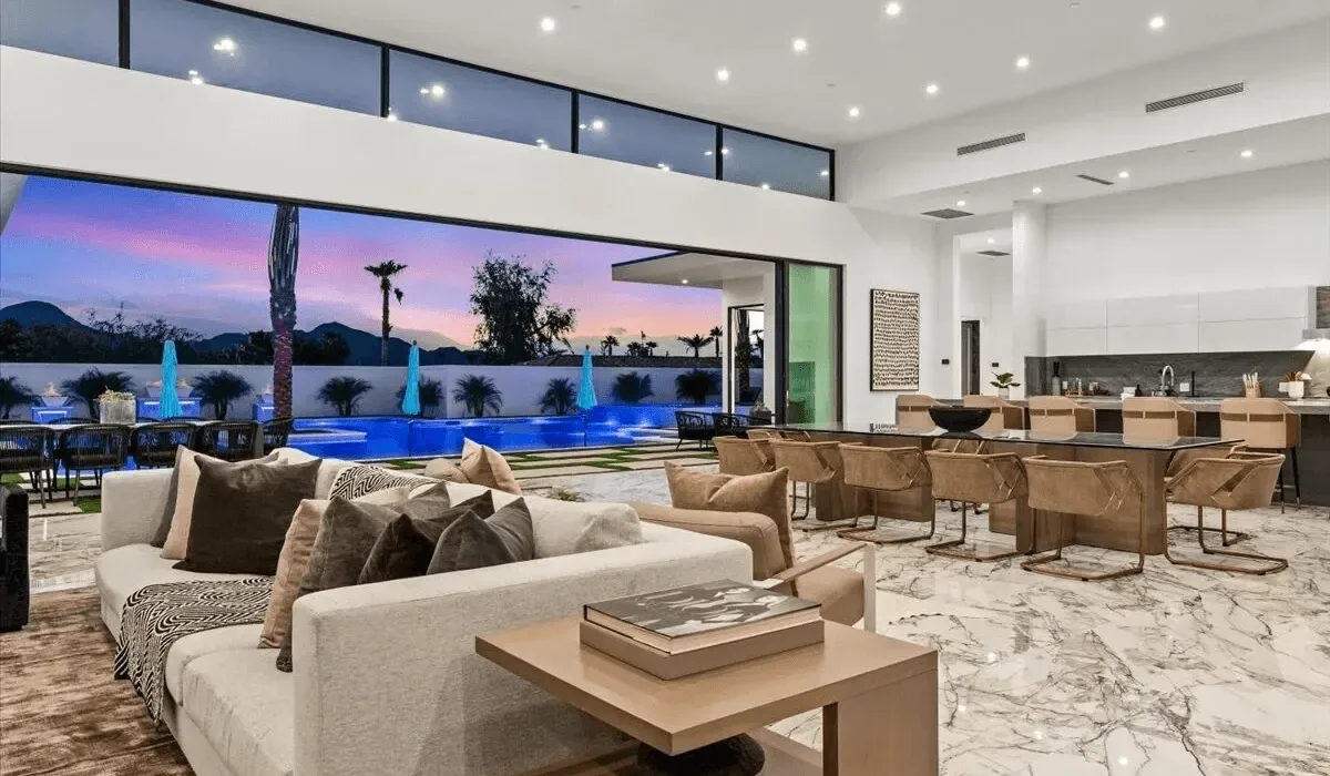 An open-plan living and dining area overlooks a pool and outdoor seating.