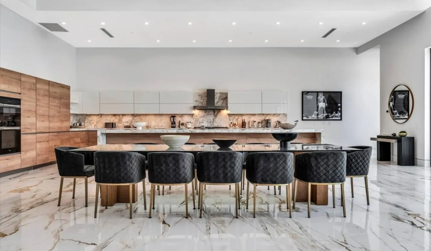 A spacious modern kitchen with a long island and dark seating.
