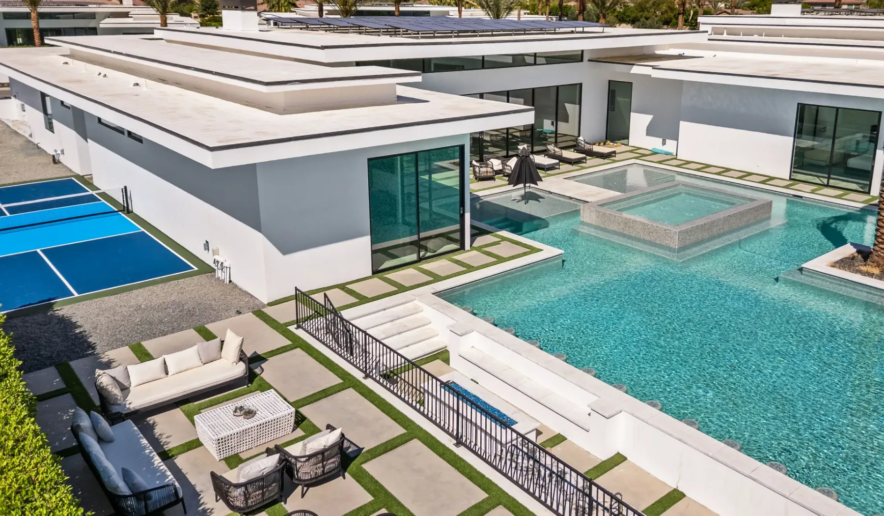 A modern pool courtyard with a raised spa and outdoor seating.