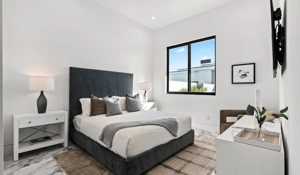 A bright bedroom with a bed beneath a large window.