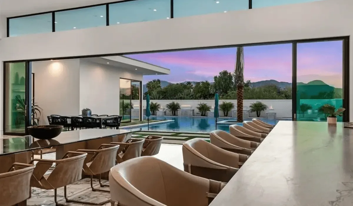 An open dining and lounge area overlooks a pool and landscaped grounds.