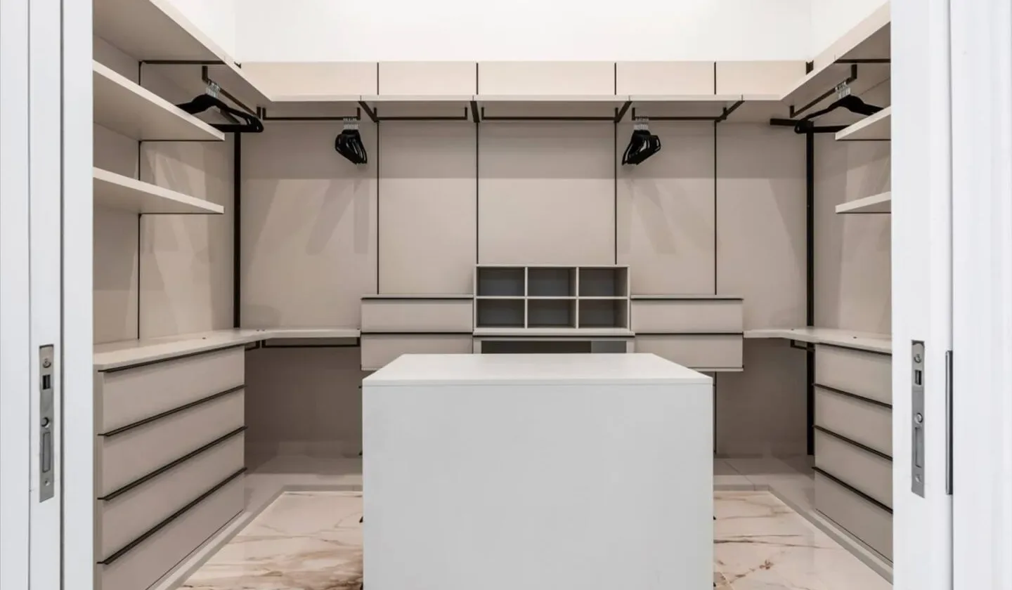 A walk-in closet with built-in shelving and a central island.