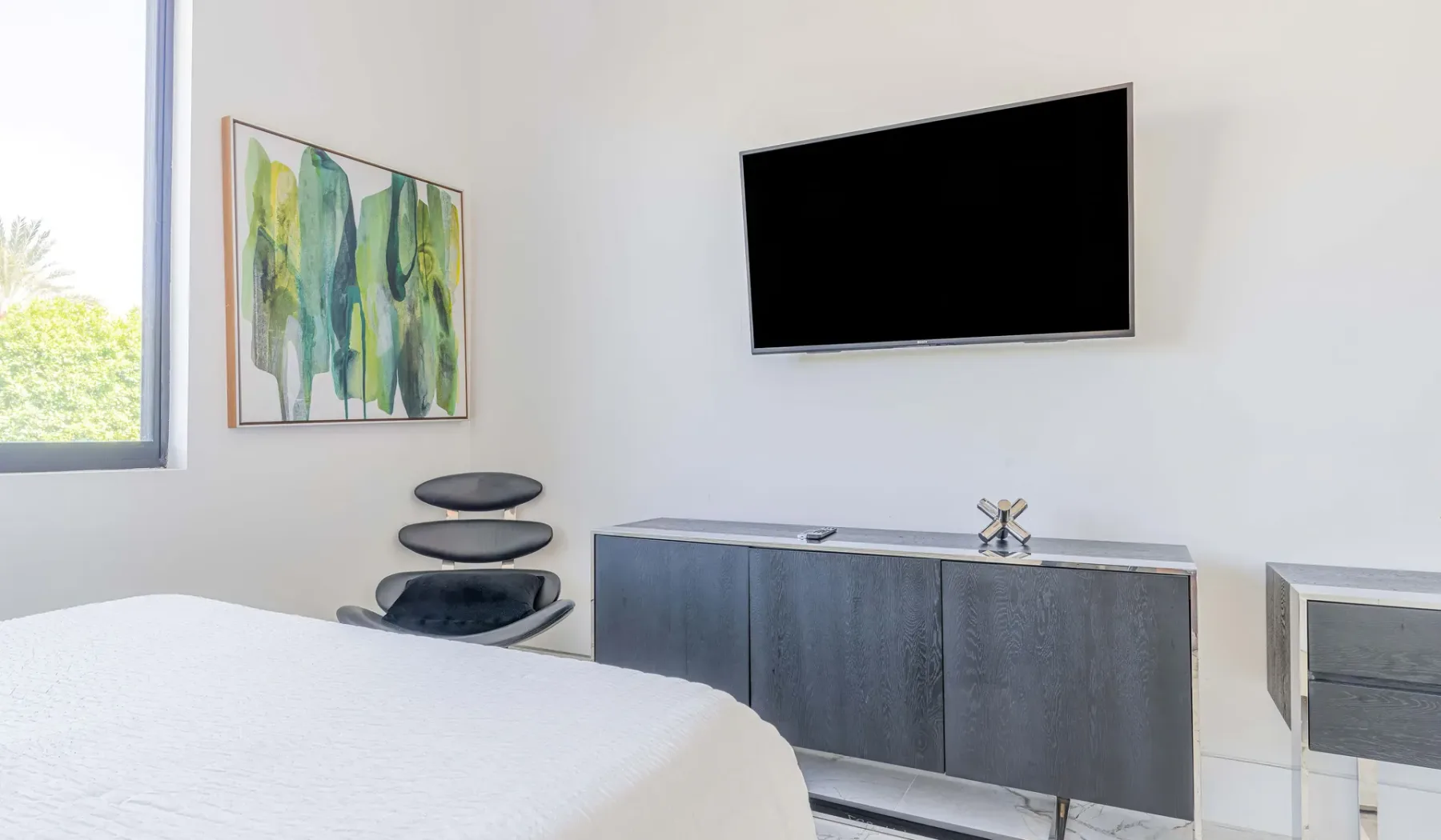 A bedroom with a wall-mounted television above a low cabinet.