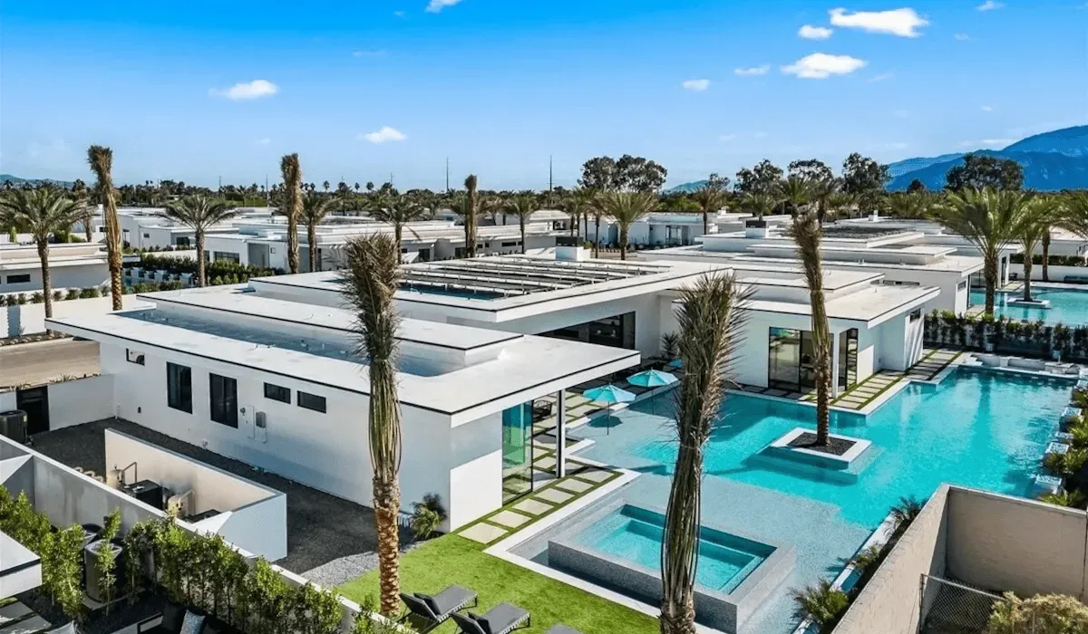 Modern low-rise buildings surround a bright turquoise swimming pool.