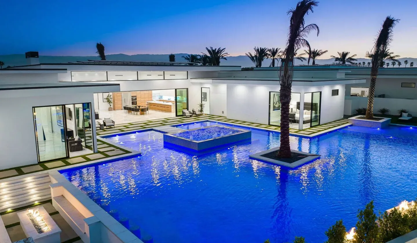 A modern building surrounds a blue swimming pool with a raised central feature.