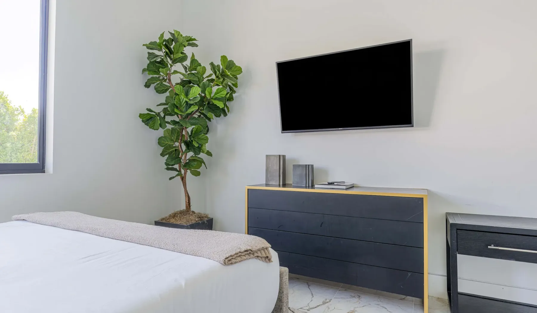 A bedroom with a bed, a wall-mounted television, and a dresser.