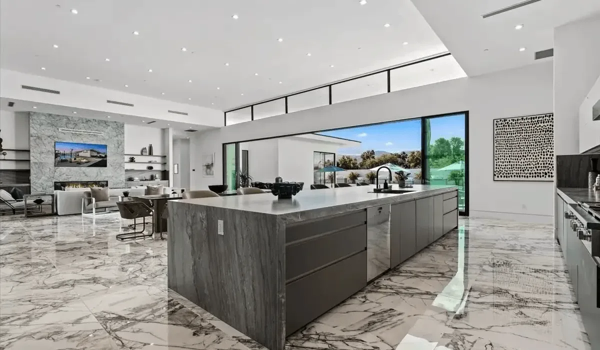A spacious modern kitchen with a large island and adjoining lounge area.