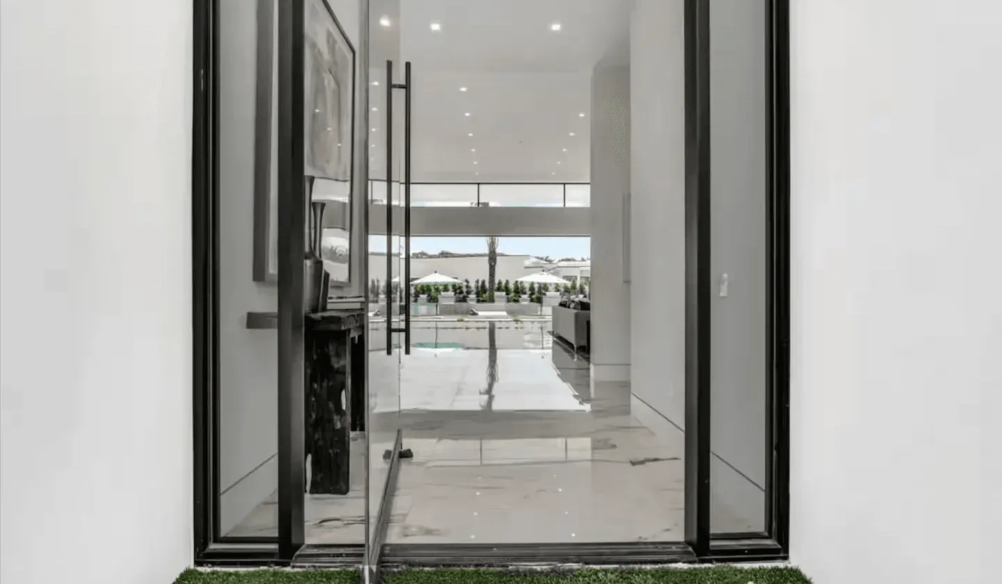 A glass doorway opens onto a bright modern interior with a view of greenery.