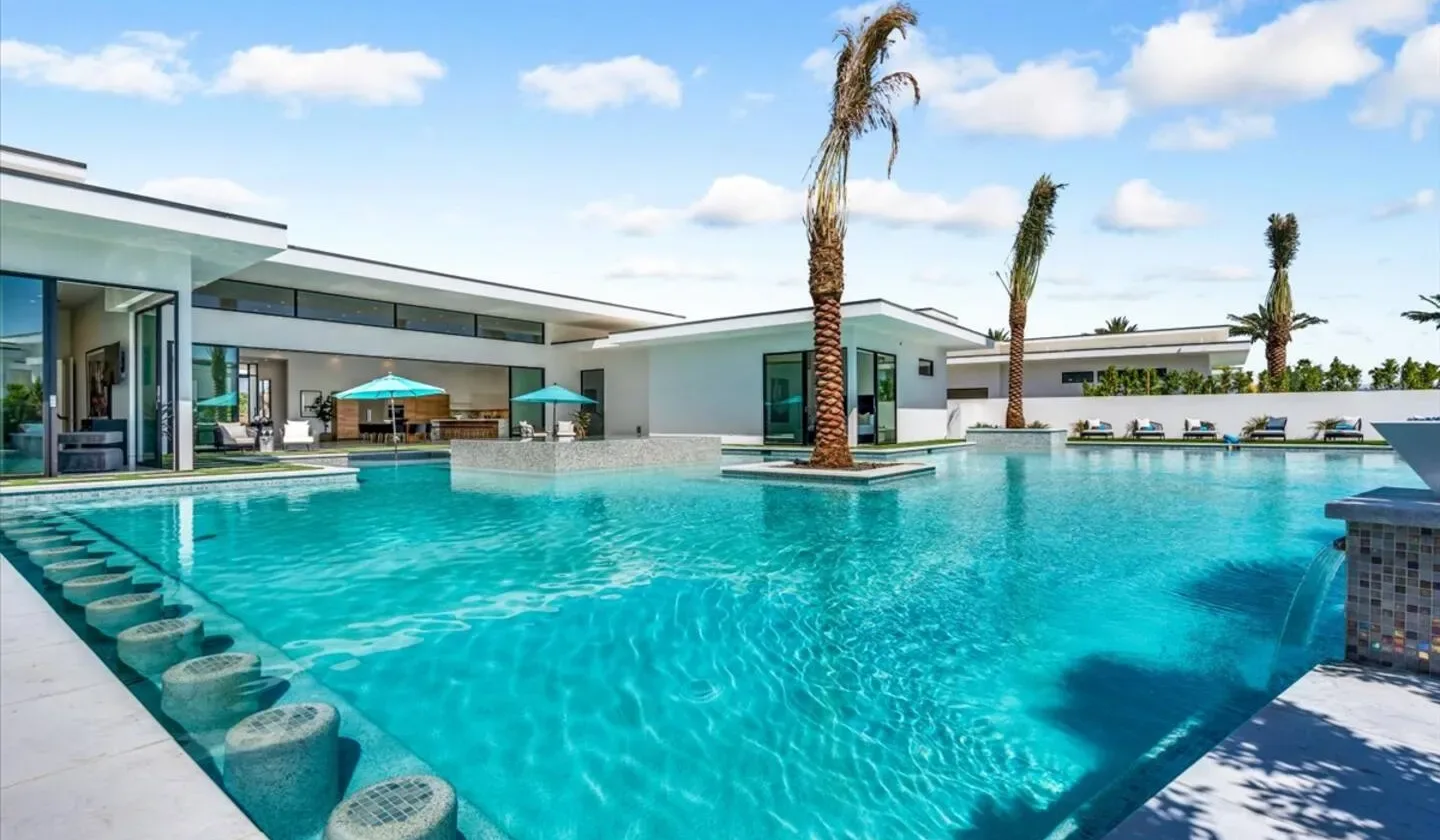 A large outdoor swimming pool beside a modern low-rise building.
