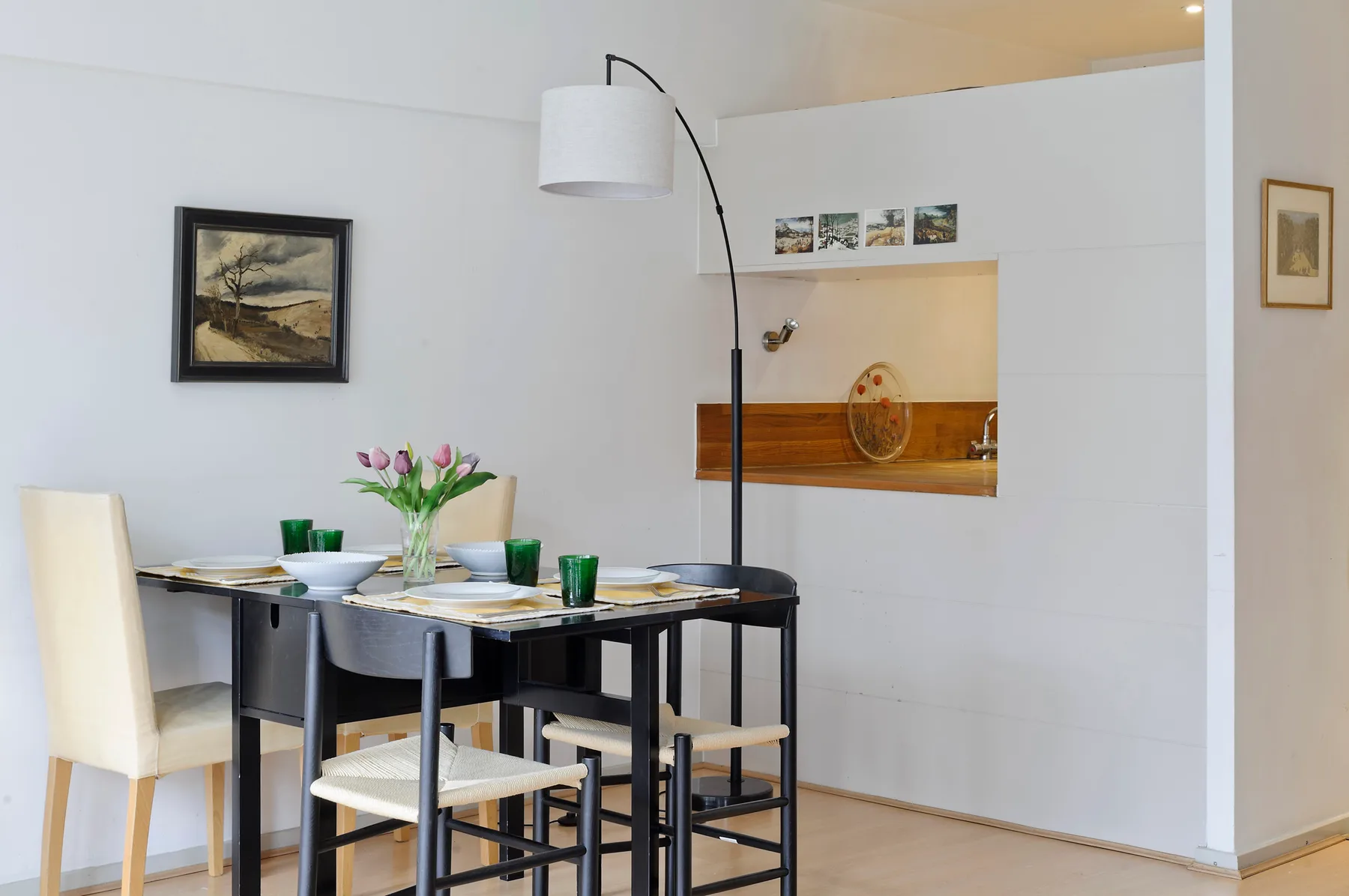 A dining area with a dark table, seating, and flowers in a vase.