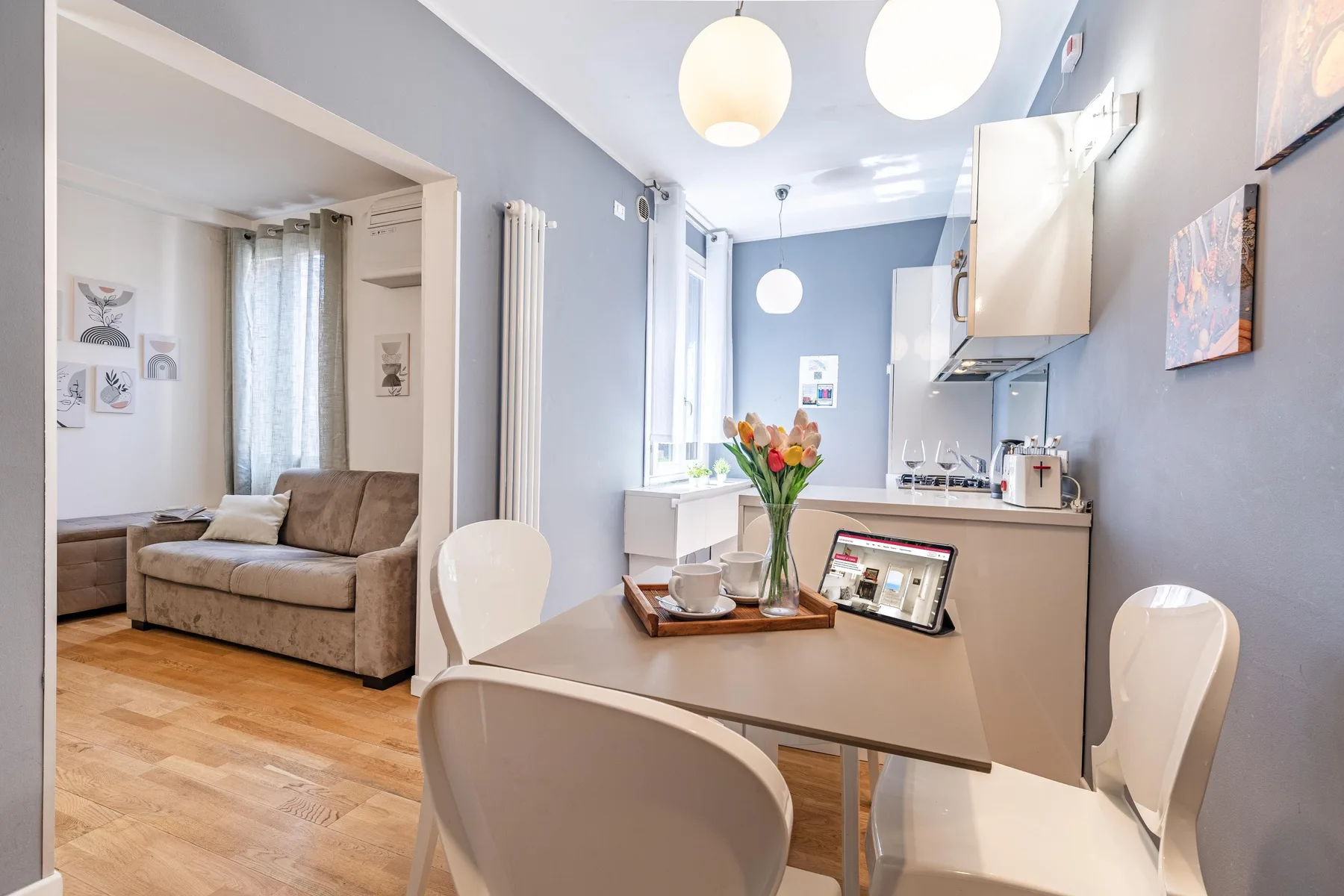 Una cocina compacta y zona de comedor con mesa, sillas y un jarrón con flores.