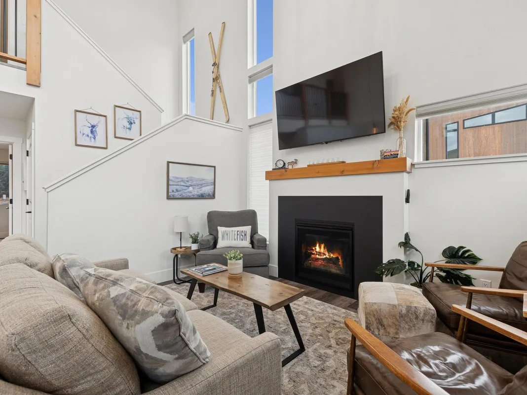 Una sala luminosa con chimenea, televisor y asientos.