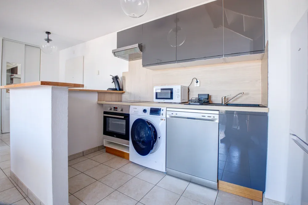 A compact kitchen with gray cabinets, a countertop, and built-in appliances.