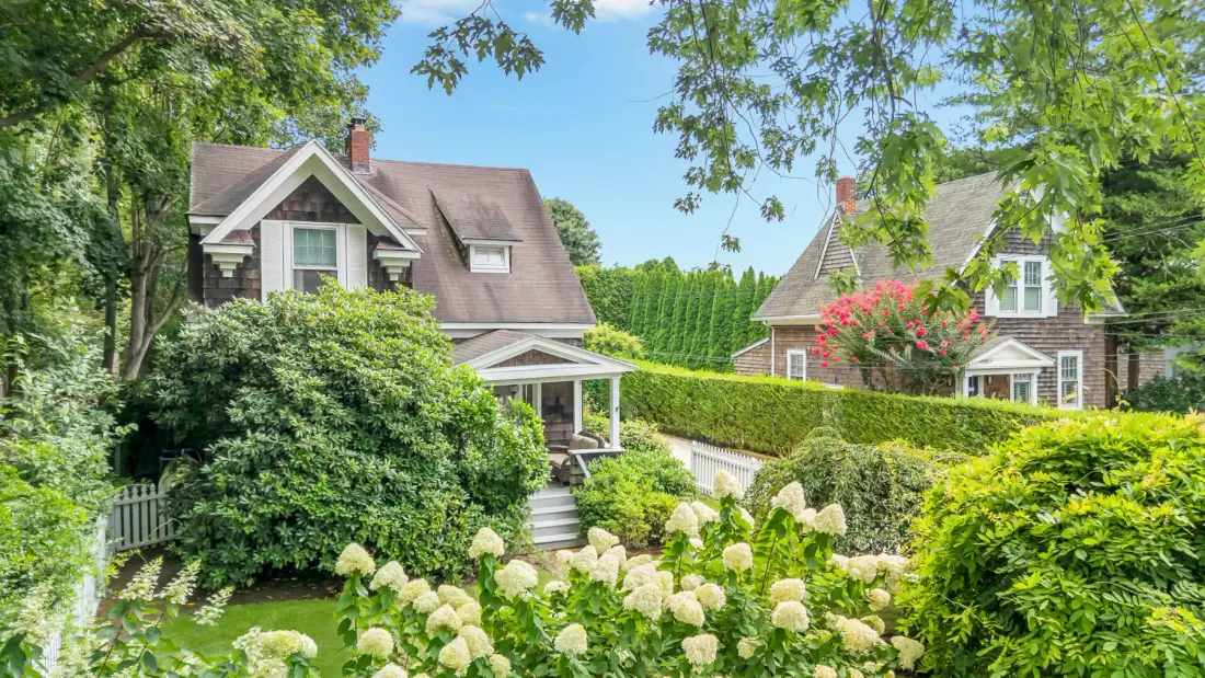 A landscaped garden with flowering shrubs in front of two houses.