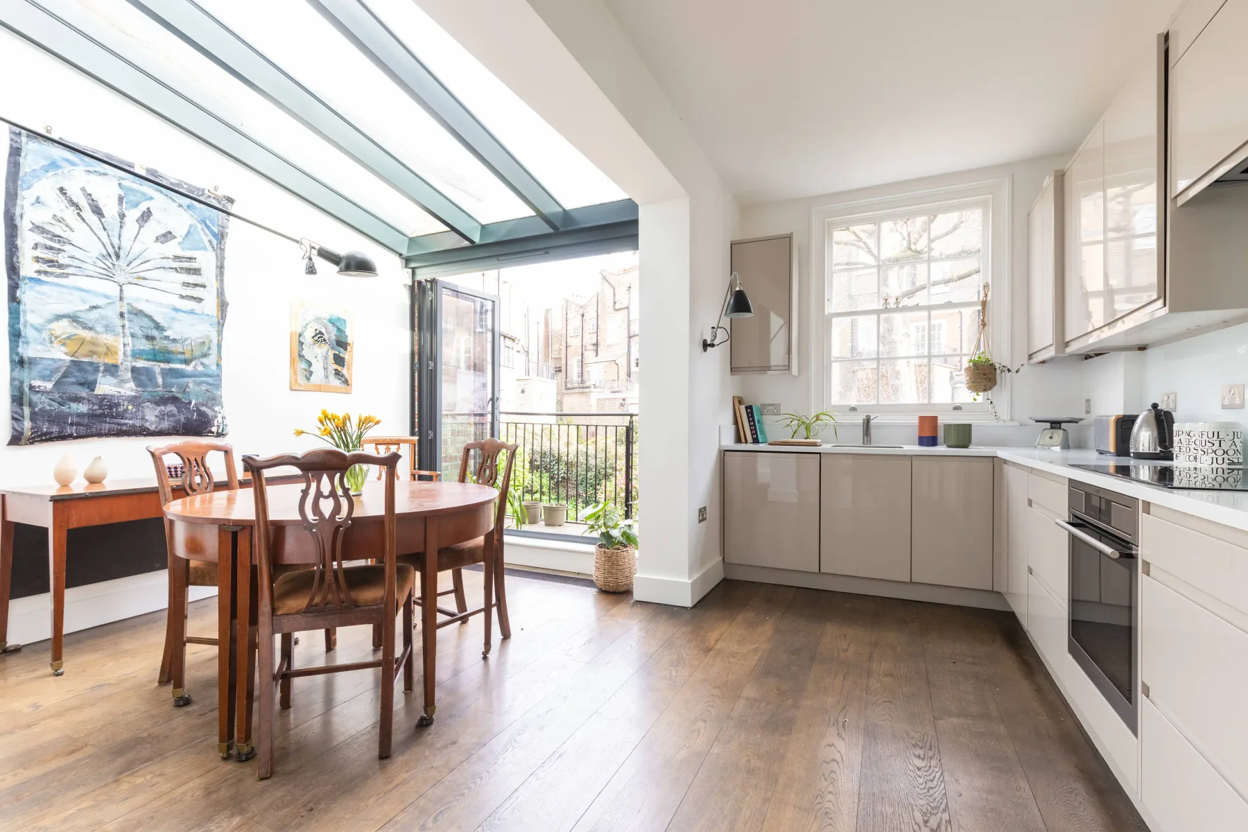 Una cocina y comedor luminosos con grandes ventanas y una mesa de comedor de madera.