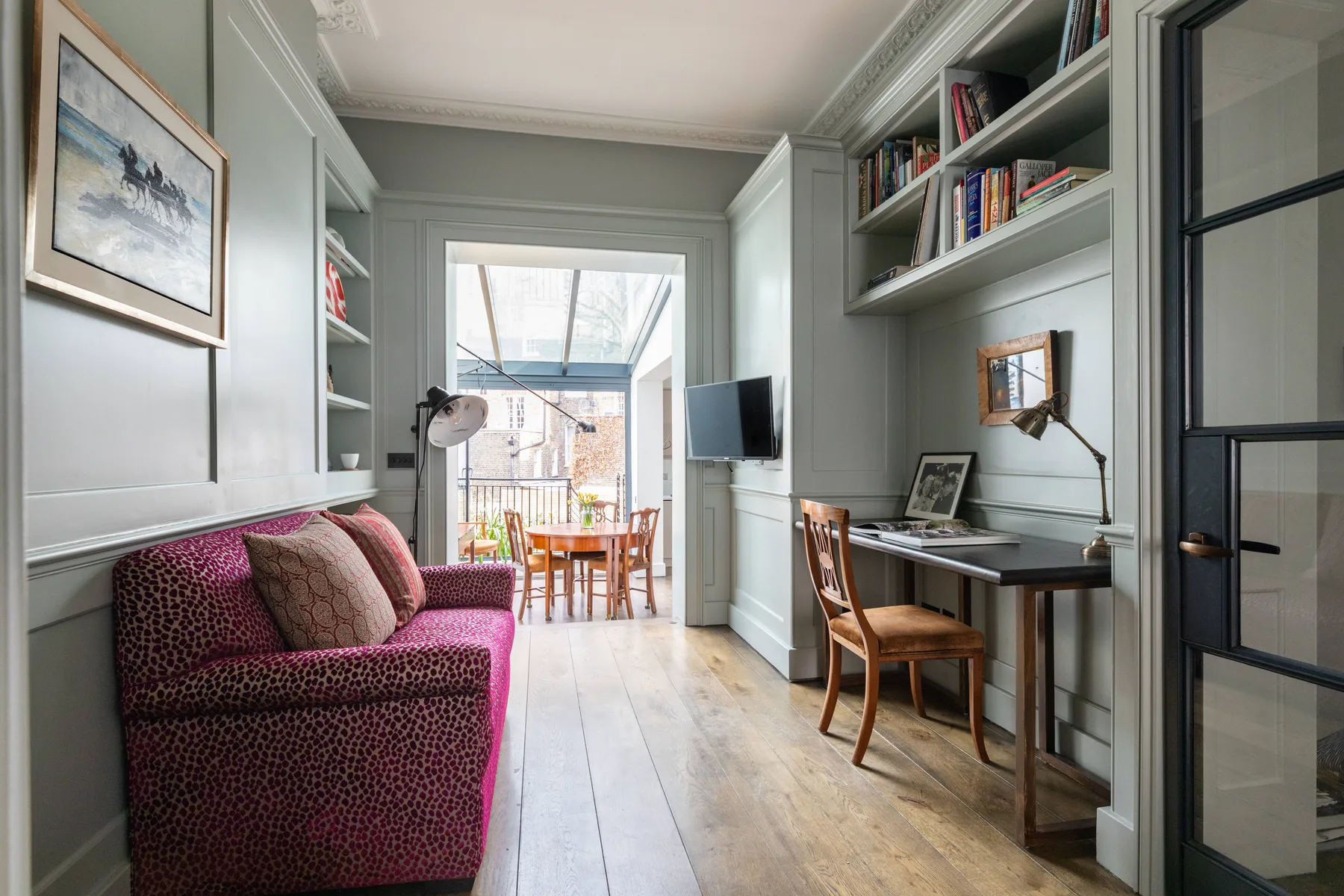 A compact study and sitting area with a desk, bookcases, and seating.