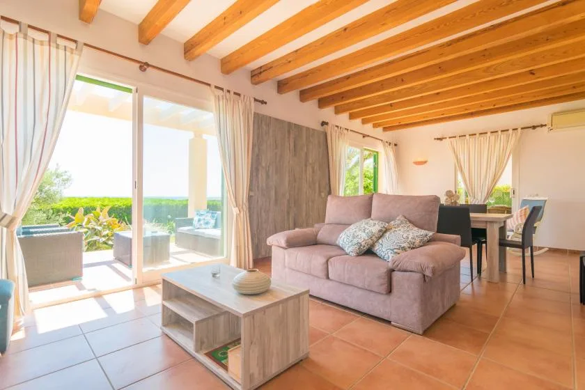 A bright living and dining area with a sofa, coffee table, and large glass doors.