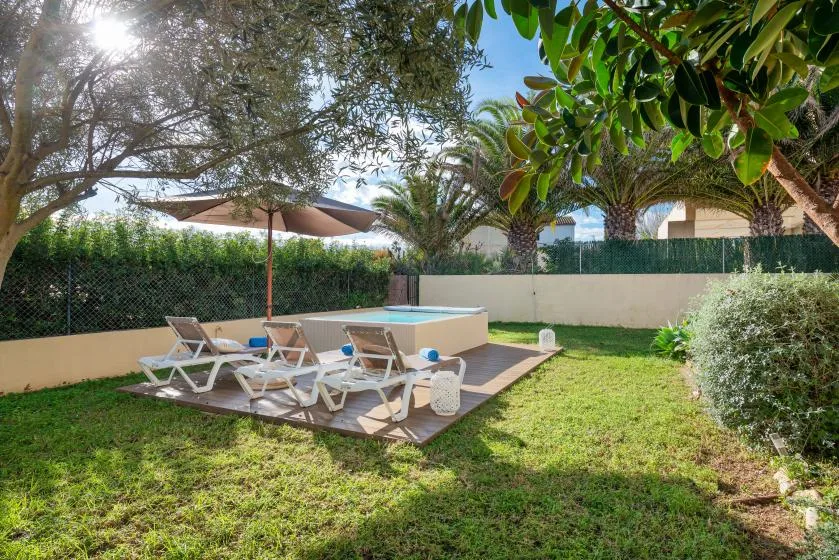 A garden patio with lounge seating and a large shade umbrella.
