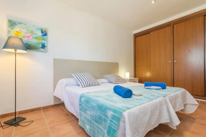 A bedroom with a neatly made bed, striped pillows, and a turquoise bedspread.