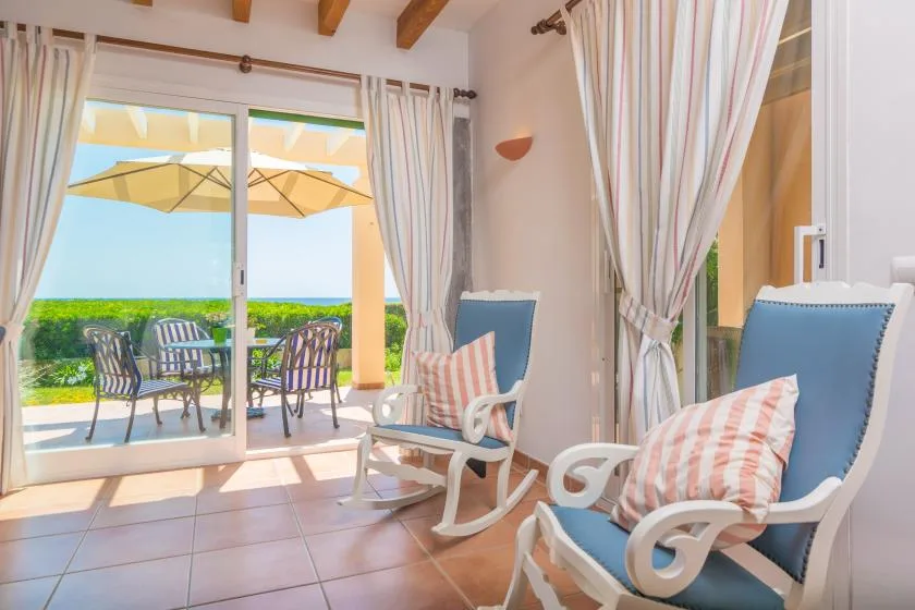 A bright sitting area with blue rocking chairs beside open patio doors.