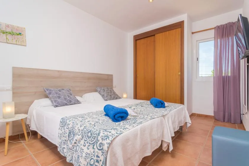 A bedroom with a double bed, patterned bedding, and a wooden wardrobe.