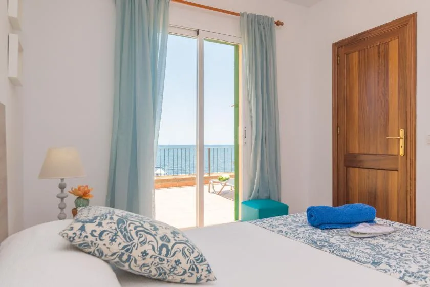 A bedroom with a bed beside a glass door opening onto a balcony.