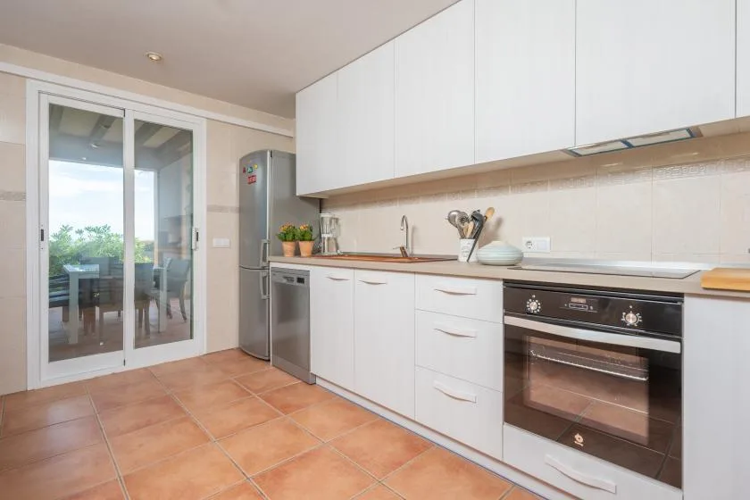 A bright kitchen with white cabinets, a countertop, and built-in appliances.