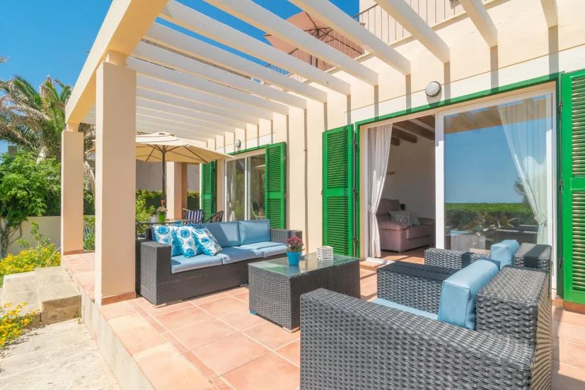 A covered patio with outdoor seating and open green shutters.