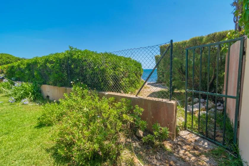 A garden path leads through an open gate toward the sea.