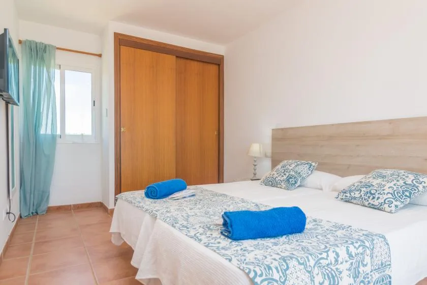 A bedroom with a double bed, patterned bedding, and blue towels.