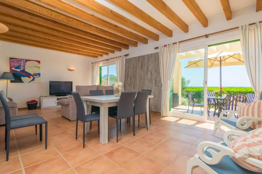 A dining and living area opens through sliding glass doors to an outdoor patio.