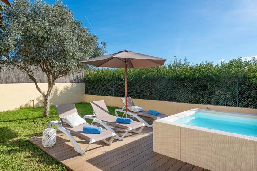 An outdoor patio with lounge seating, a sun umbrella, and a small pool.
