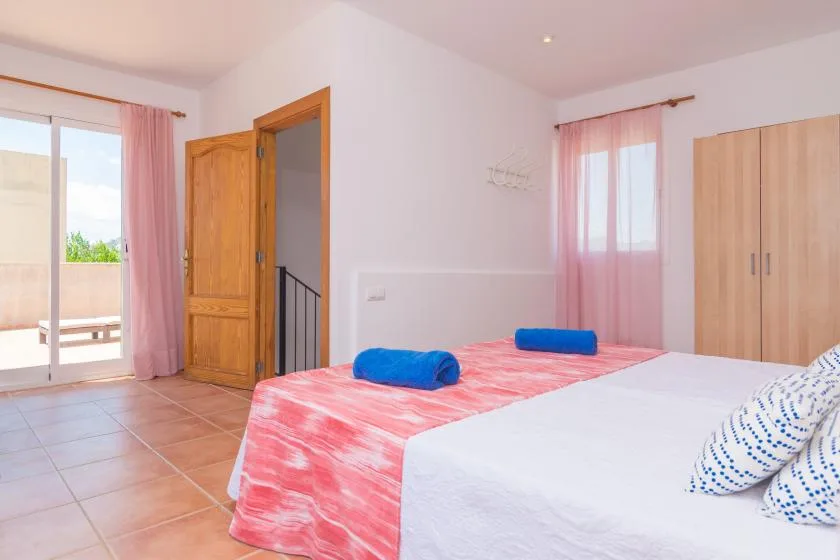 A bedroom with a bed covered in pink bedding and a wooden wardrobe.