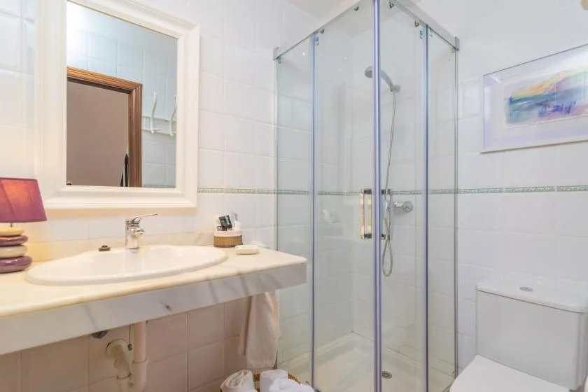 A bright bathroom with a sink, glass shower, and toilet.