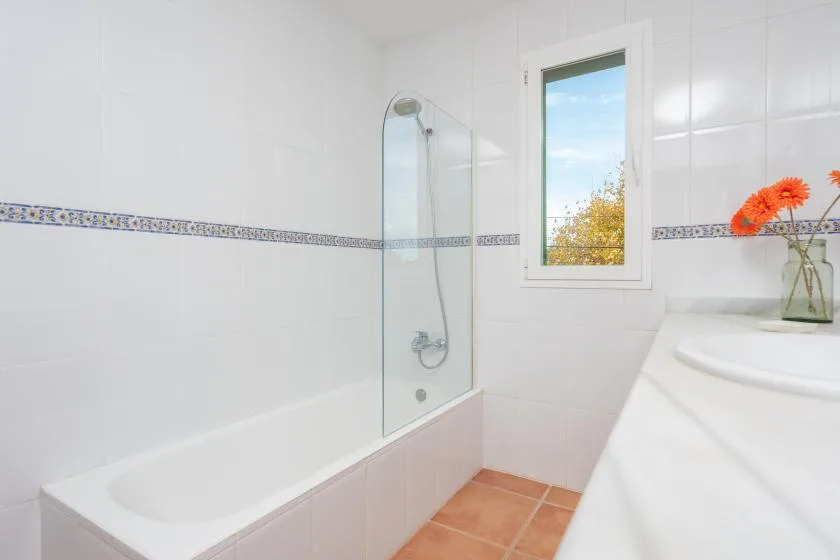 A bright bathroom with a bathtub, shower, and window.