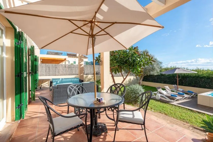 A sunny patio with outdoor seating overlooks a poolside area.