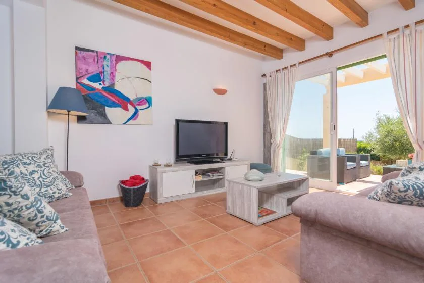 A bright living room with seating, a television, and glass doors opening to a patio.