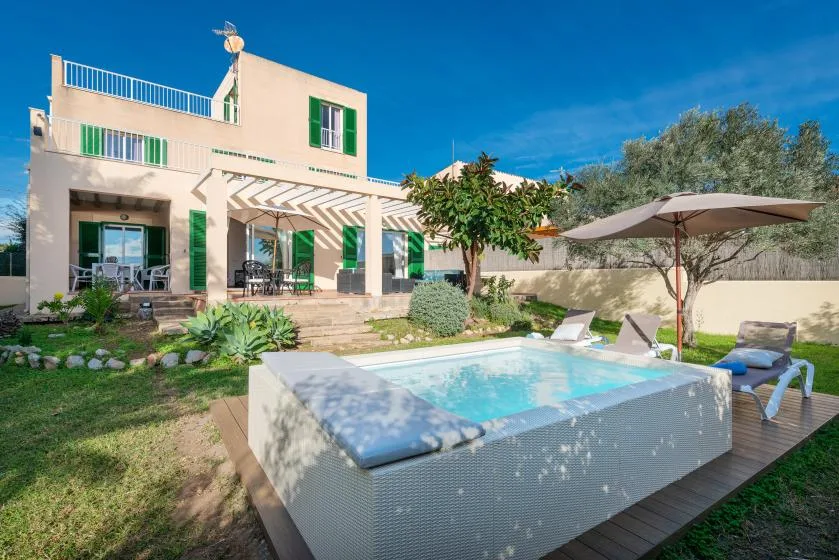 A house with a swimming pool and shaded outdoor seating.