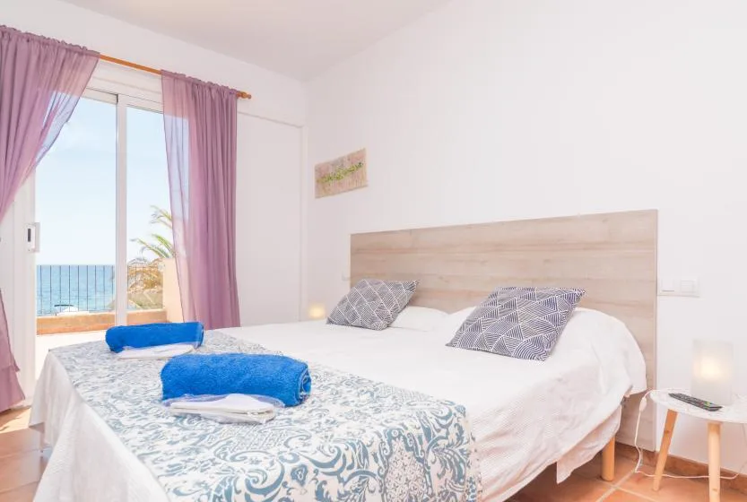 A bedroom with a double bed, patterned bedding, and a window overlooking the sea.