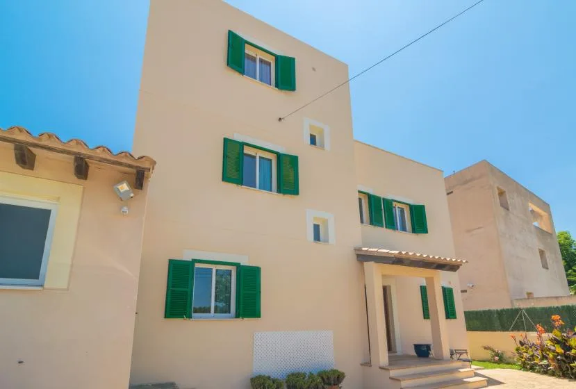 A beige multi-story building with green shutters and a covered entrance.