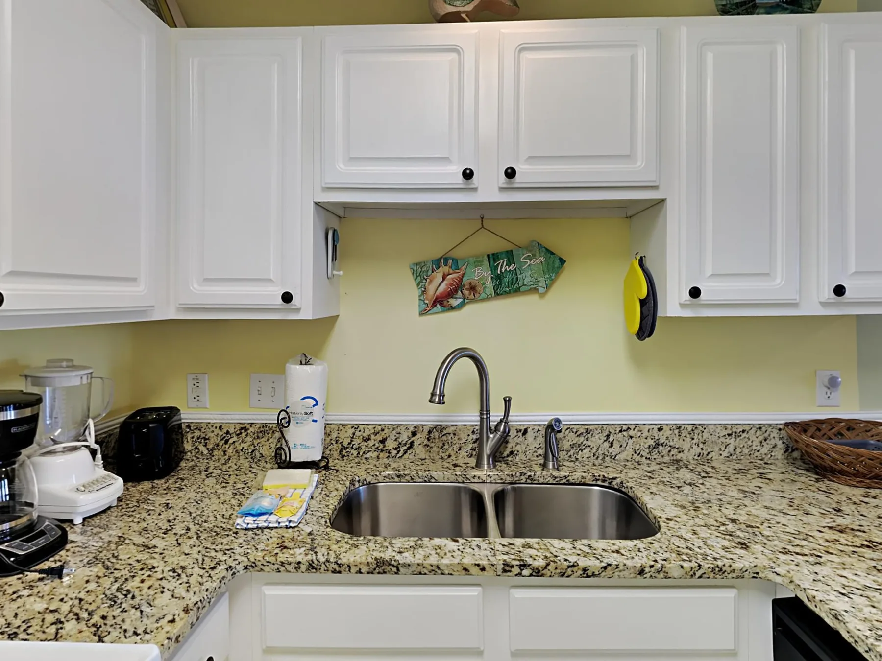 A kitchen counter with a double sink, cabinets, and small appliances.