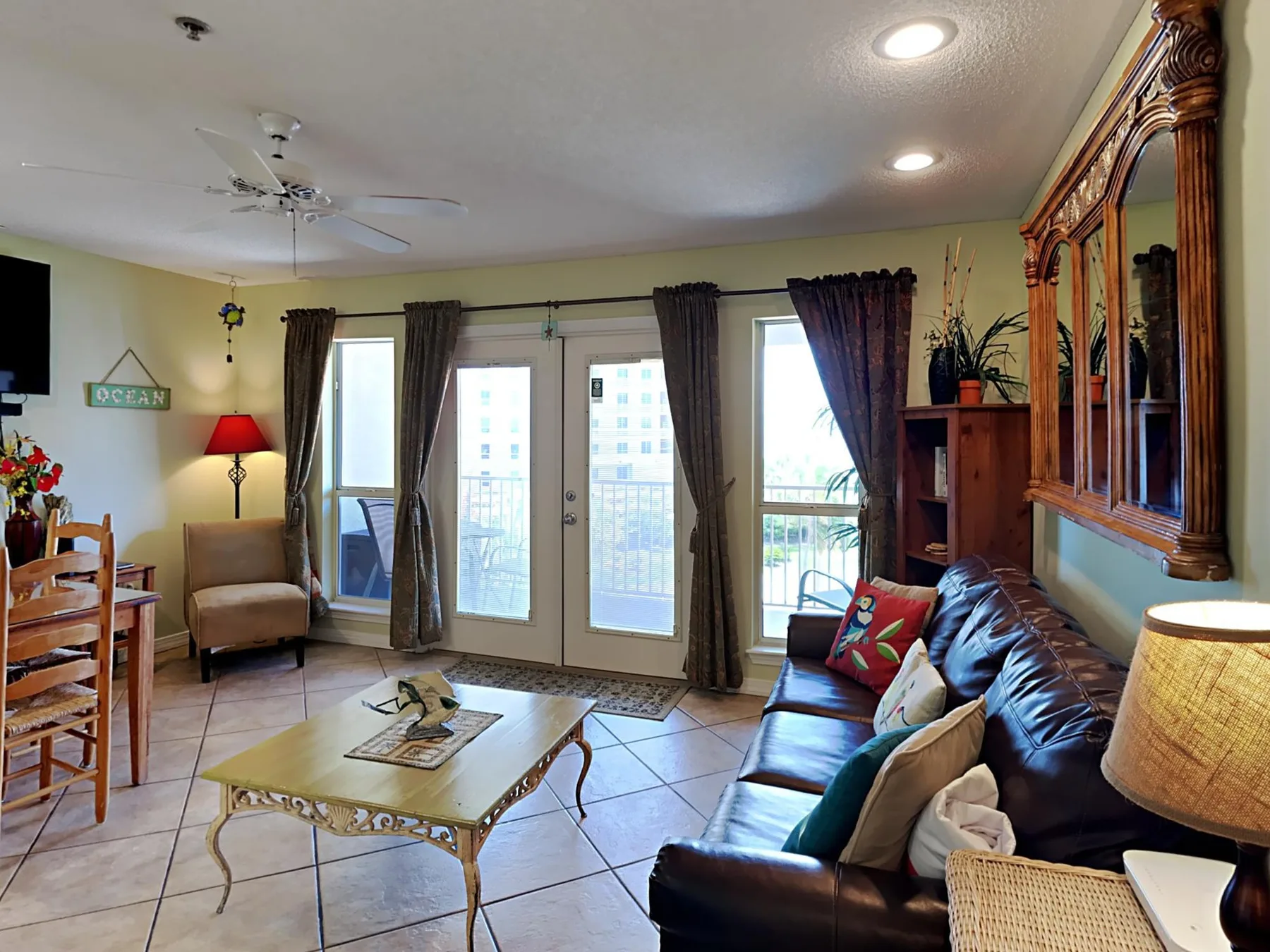 A living room with seating, a coffee table, and glass doors opening to a balcony.