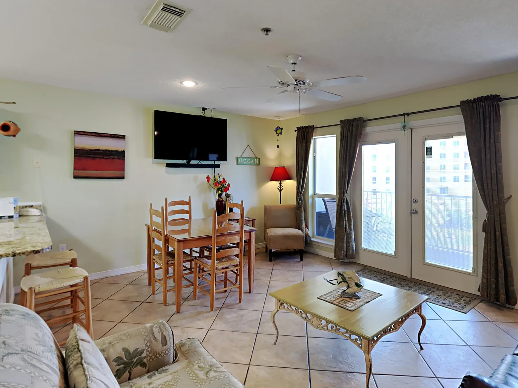 A living and dining area with seating, a dining table, and glass doors.