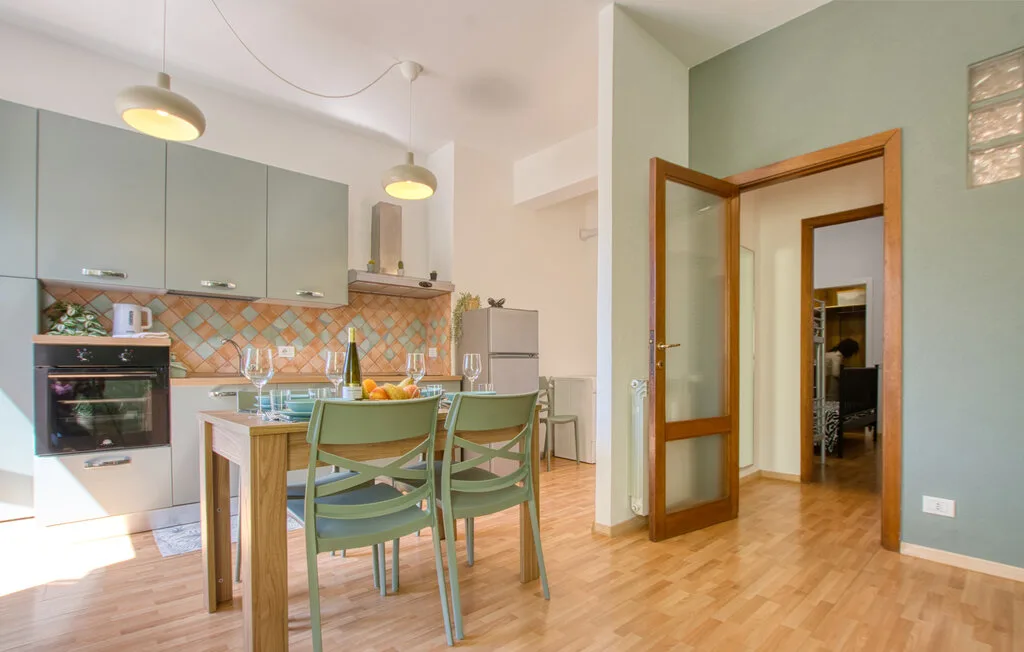 Una cocina y comedor con asientos verdes, armarios y una puerta abierta.