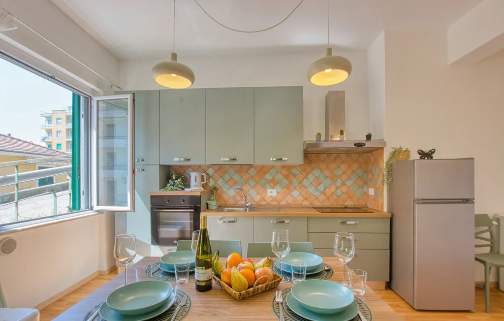 Una luminosa cocina con comedor y una mesa puesta junto a una ventana abierta.