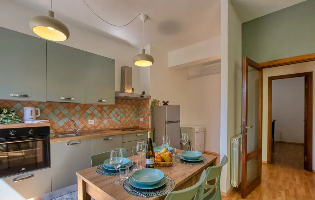 Cocina y comedor con una mesa puesta con platos y un frutero.