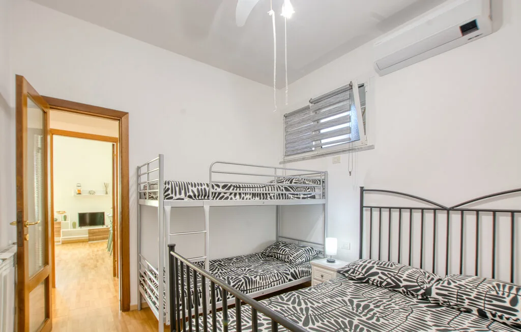 Un dormitorio con literas, otra cama y una ventana pequeña.